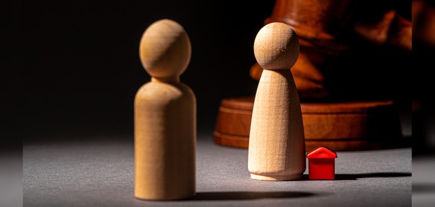 A wooden gavel, 2 wooden pieces representing people, and a red house indicating how to divide a business in high net worth divorce