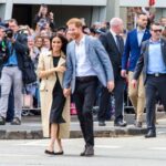 Prince Harry & Meghan Markle smiling in a crowd being photographed to indicate they Have Less Privacy in U.S.
