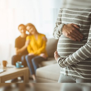 A surrogate mother holds her belly as an excited couple watches happily in the backgroundLegal Aspects of Surrogacy Explained by Celebrity Divorce Lawyer Christopher C. Melcher
