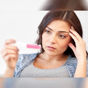 Sad unhappy woman looking at pregnancy test, indicating the Relationship between infertility and divorce