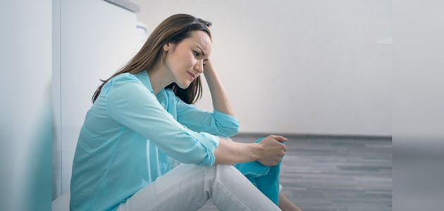 Upset woman sitting on the floor of a house