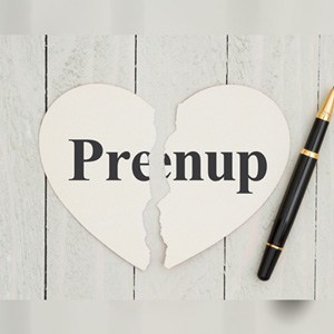Heart-shape Prenup card ripped in half on wood background next to a pen