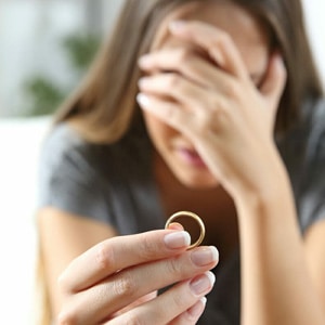 A woman holding a wedding ring with her hand over her head