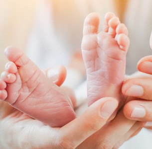 Parent with baby's feet in their hands