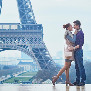 A couple kisses in front of the Eiffel Tower in Paris, France