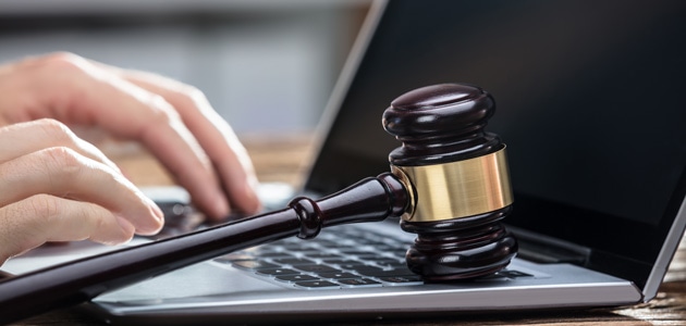 man typing on a laptop computer with gavel on it
