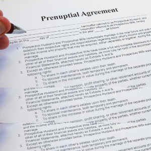 A person reviewing a prenuptial agreement with fingers and a pen over the contract