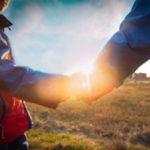 Parent and child holding hands outdoors at sunset representing California move-away and child custody litigation